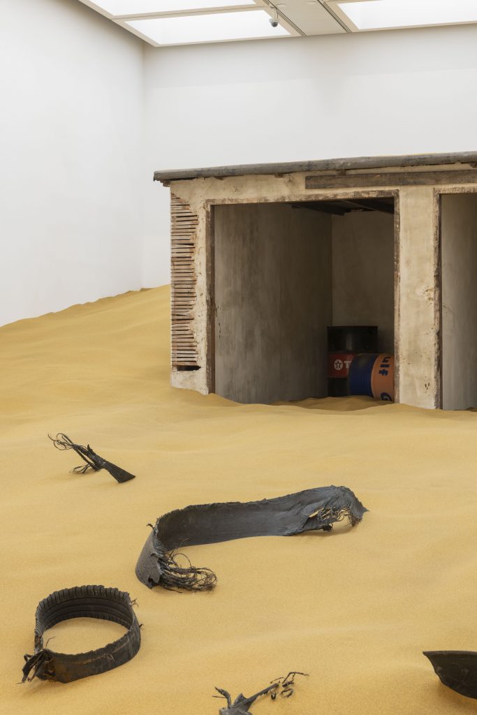 Installation view of Mike Nelson, Triple Bluff Canyon (the woodshed), 2004. Various materials. M25, 2023. Found tyres. Photo: Matt Greenwood. Courtesy the artist and the Hayward Gallery.