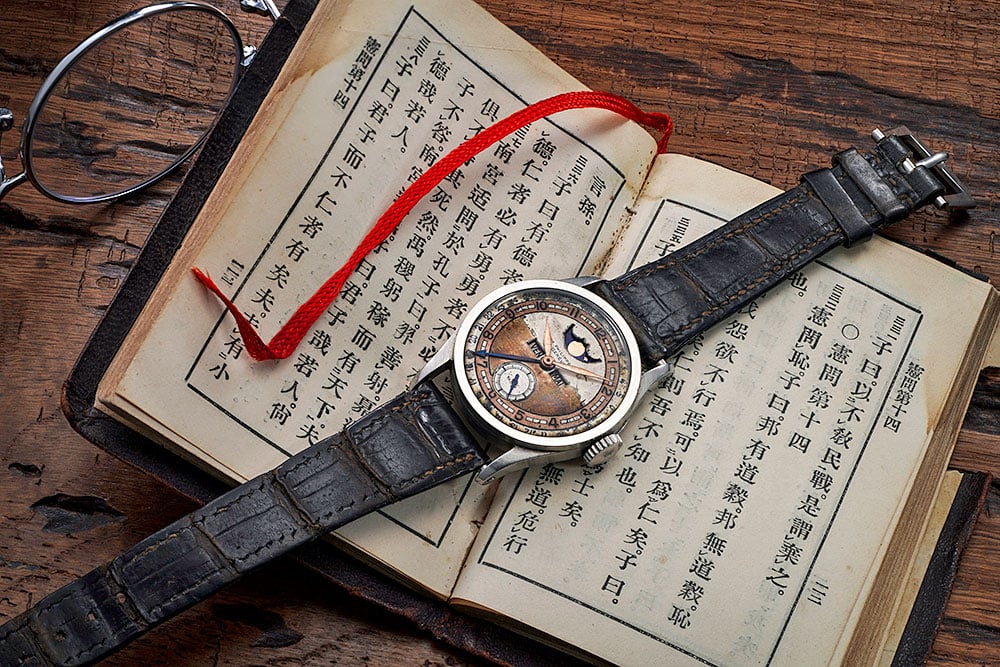 A Patek Philippe Reference 96 Quantieme Lune and a leather-bound printed edition of Confucius’s <em>Analects</em>, formerly from the collection of Aisin-Giro Puyi. Courtesy of Phillips.