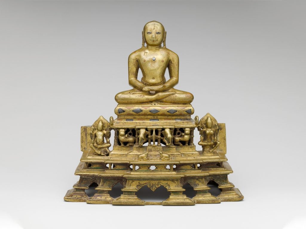 Svetambara Enthroned Jina, with Attendant Yaksha and Yakshi (second half of the 11th century C.E.). Copper alloy inlaid with silver and copper. Photo courtesy of the Metropolitan Museum of Art, New York.