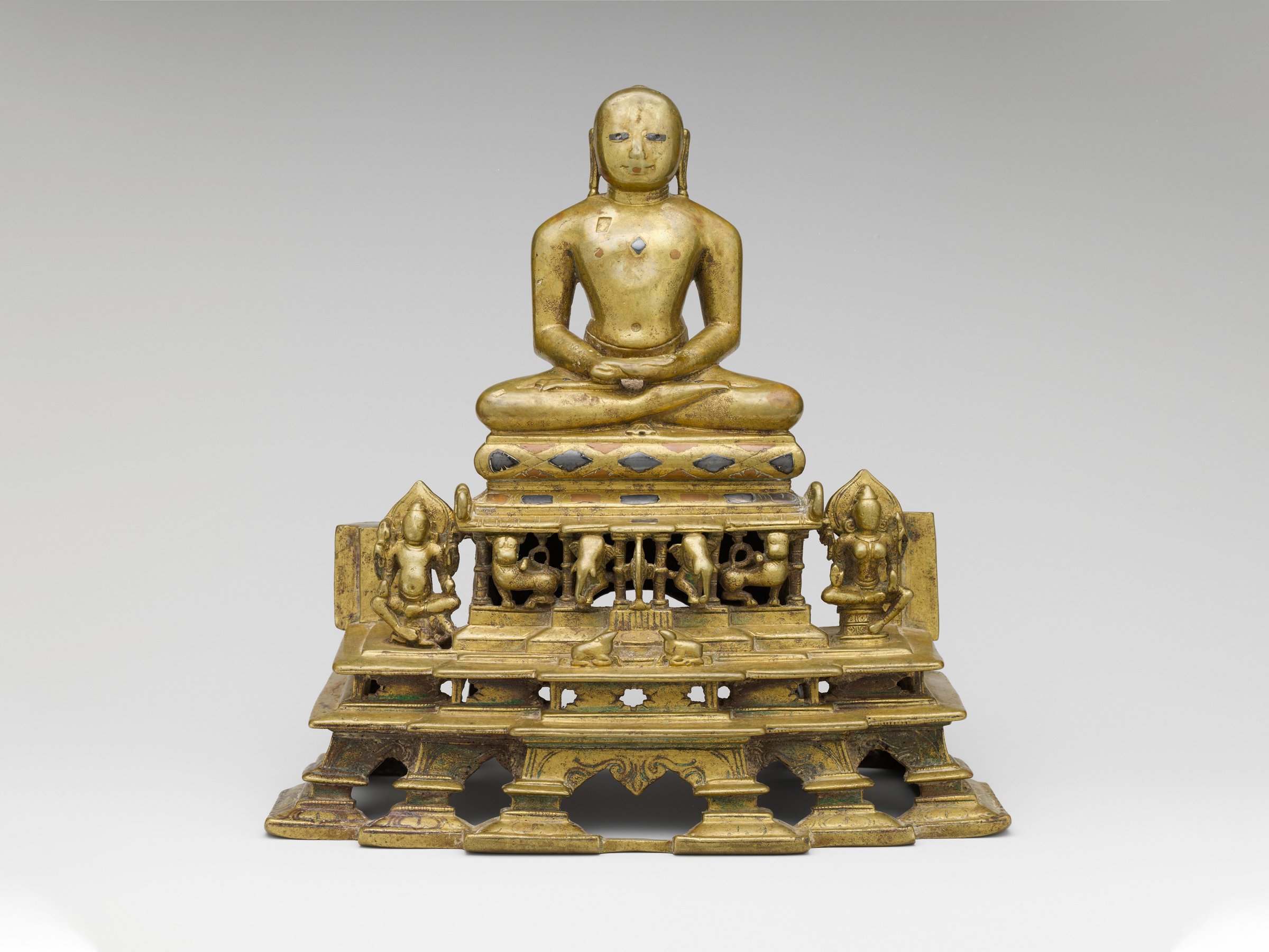 Svetambara Enthroned Jina, with Attendant Yaksha and Yakshi (second half of the 11th century C.E.). Copper alloy inlaid with silver and copper. Photo courtesy of the Metropolitan Museum of Art, New York.