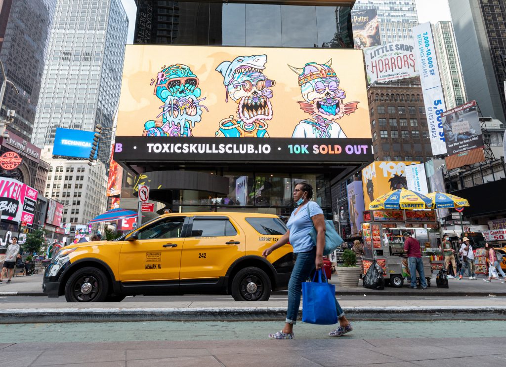 A person walks by a 'Toxic Skulls Club' NFT billboard in Times Square