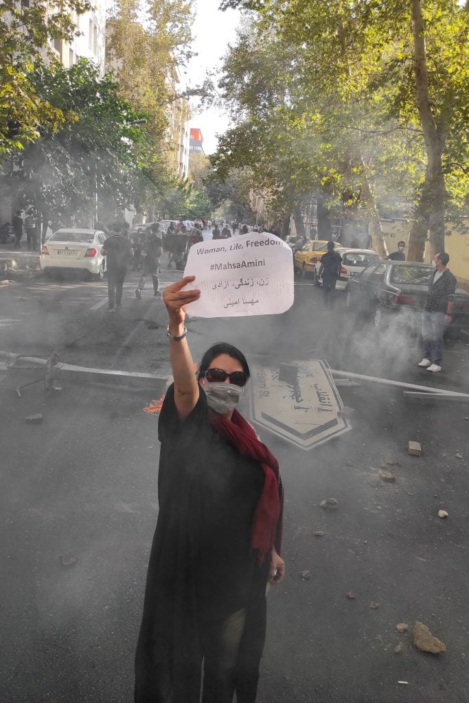 A protester holds up a note reading "Woman, Life, Freedom, #MahsaAmini" while marching down a street on October 1, 2022 in Tehran, Iran. Photo by Getty Images.