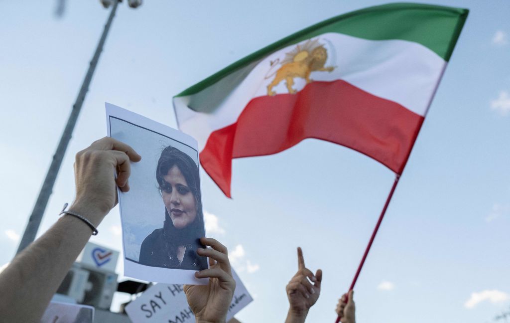 A protestors holds a photo of Kurdish Iranian woman Mahsa Amini as another waves Iran's former flag during a demonstration against the Iranian regime and in support of Iranian women in October. Photo by Bulent Kilic/AFP via Getty Images.