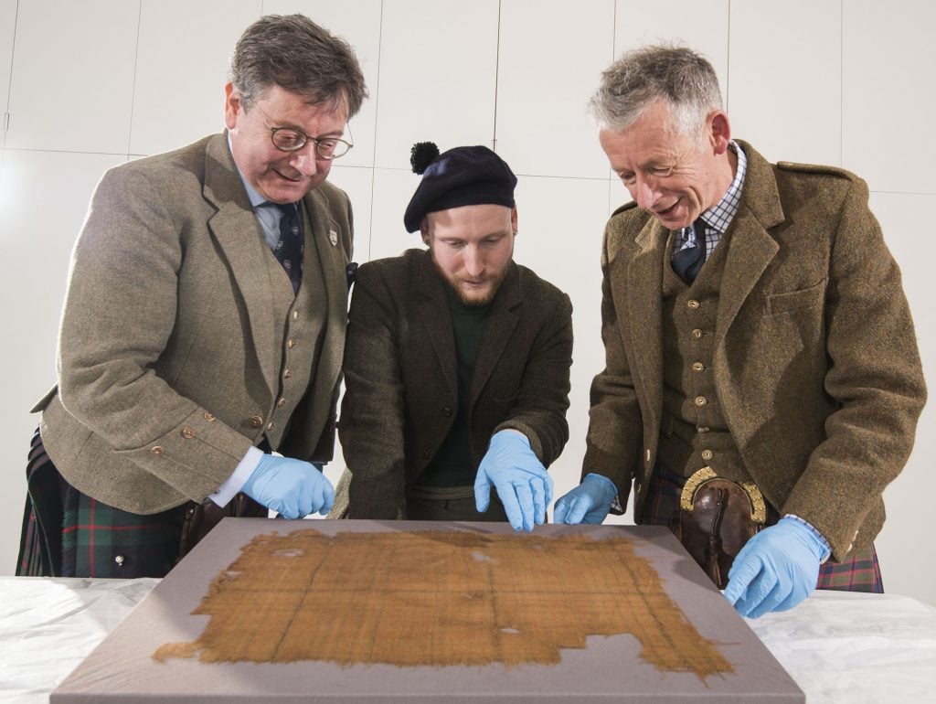 From left: John McLeish, chair of the Scottish Tartans Authority; James Wylie, an assistant curator at V&A Dundee, and Peter MacDonald, head of research and collections at V&A Dundee, examining the Glen Affric tartan. Photo: Alan Richardson, courtesy of V&A Dundee.