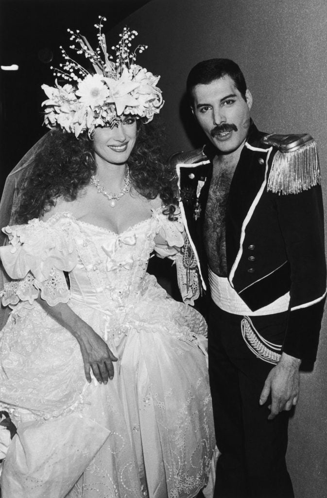 Jane Seymour in a white ballgown with Freddie Mercury in a military-style dress uniform during the Fashion Aid benefit concert at the Royal Albert Hall, London, 5th November 1985. (Photo by Dave Hogan/Hulton Archive/Getty Images)