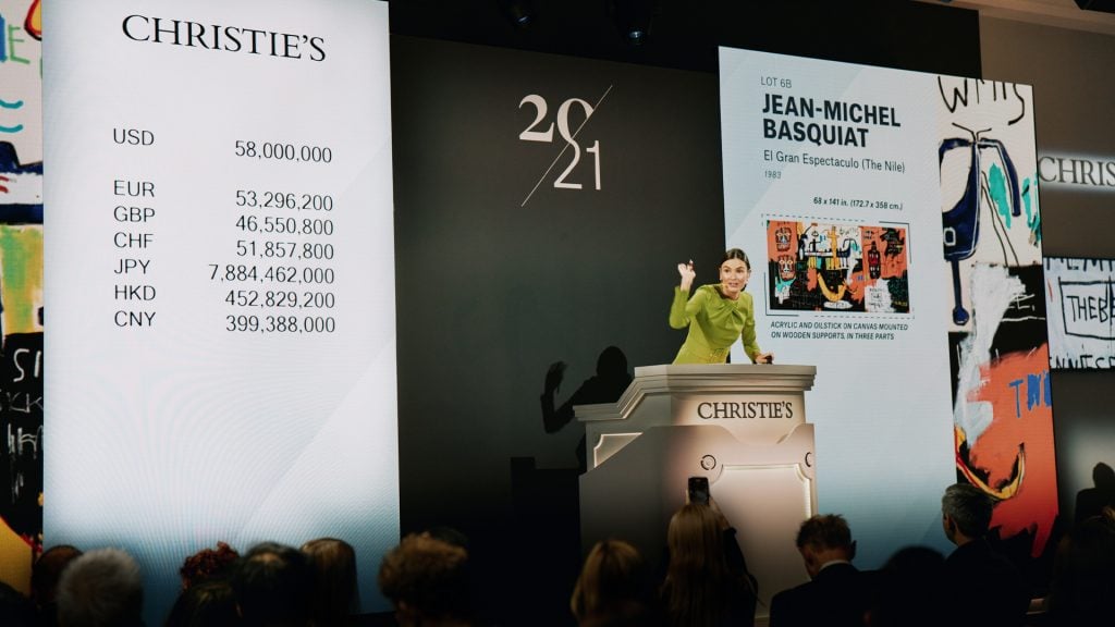 Auctioneer Georgina Hilton selling the top lot, Jean-Michel Basquiat's El Gran Espactaculo (The Nile) (1983) at Christie's evening sale of 21st Century Art in New York on May 15. Image courtesy Christie's.
