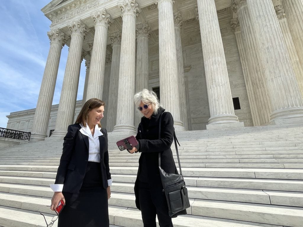 Lynn Goldsmith poses for a photo with attorney Lisa Blatt on the steps of the Supreme Court for the <em>Warhol v. Goldsmith</eM> case on October 12, 2022 in Washington, D.C. Photo by Mickey Osterreicher/Getty Images.