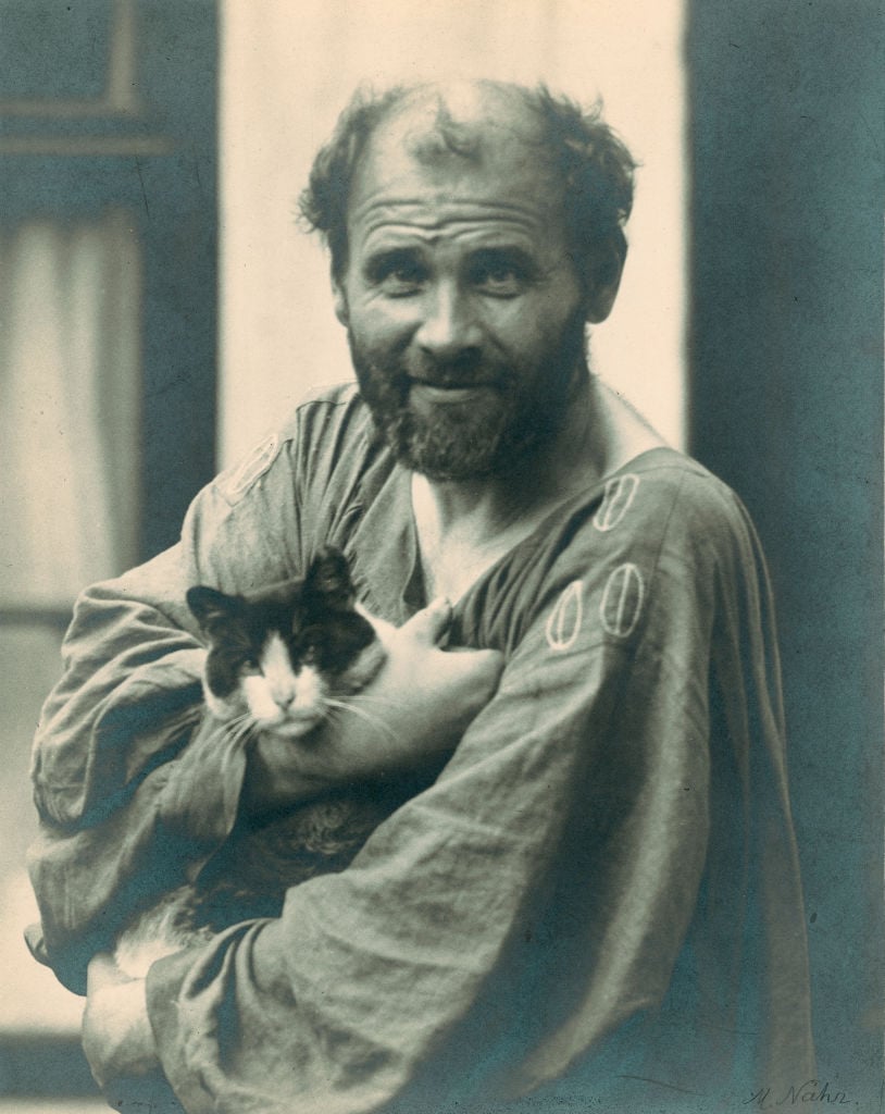 Gustav Klimt holding one of his cats in his arms, in front of his studio in Vienna, 8th district, Josefstaedter Strasse (ca. 1912). Photo: Moriz Naehr. Courtesy of Imagno/Getty Images.