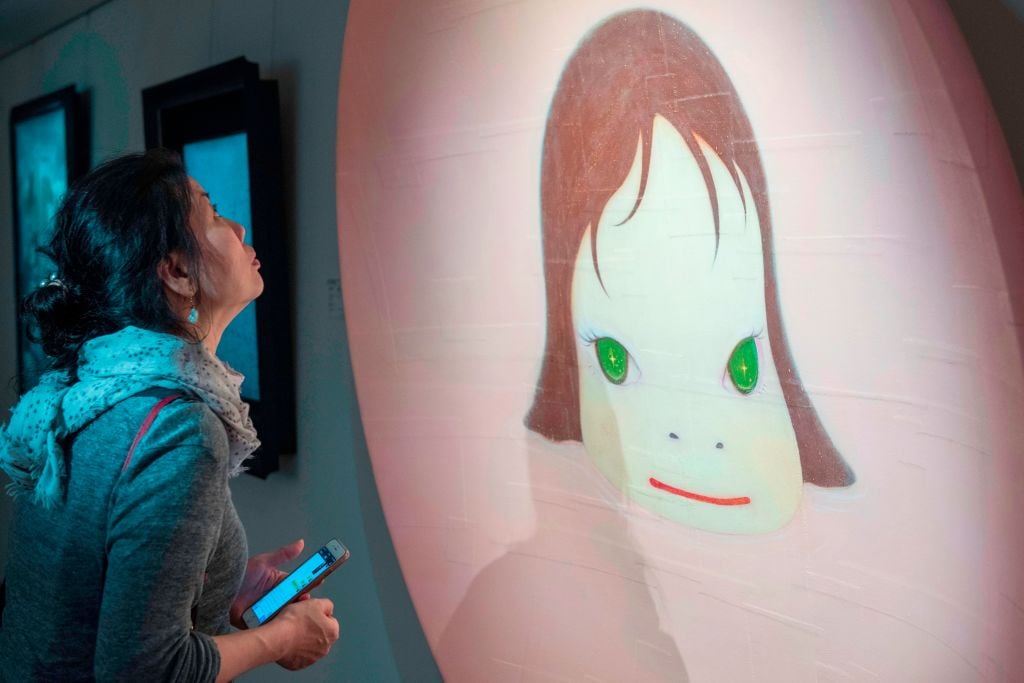 A woman looks at Japanese artist Yoshitomo Nara's 'In the Pinky Lake' during a media preview of Christie's Hong Kong Spring Sales in Hong Kong on March 30, 2018. Photo by Philip Fong/AFP via Getty Images.