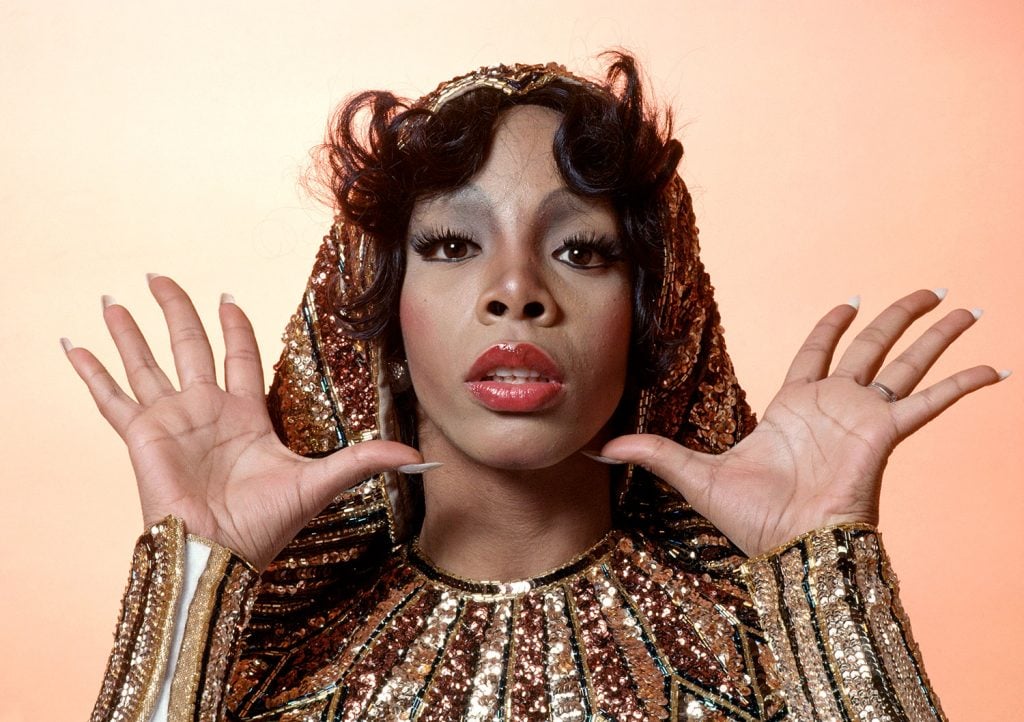 Headshot of Donna Summer, wearing gold-sequined cuffs and collar, 1976. (Photo by Fin Costello/Redferns/Getty Images)
