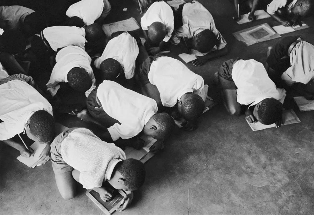 Ernest Cole, from <em>House of Bondage</em>. Students kneel on the floor to write. The government did not always provide schools for black children. Photo ©Ernest Cole, courtesy of Magnum Photos.