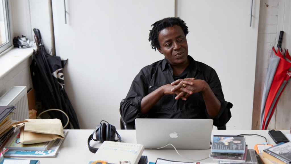 artist john akomfrah who is representing the U.K. at the Venice Biennale, sitting at his computer in a studio space in London