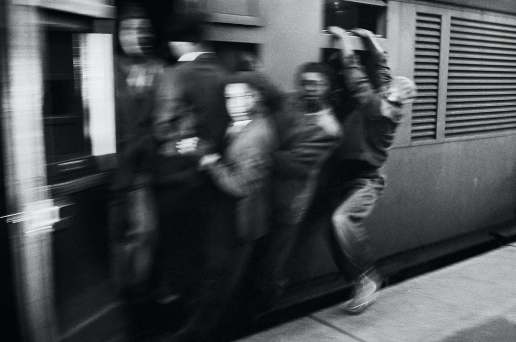 Ernest Cole, from <em>House of Bondage</em>. Africans throng Johannesburg station platform during late afternoon rush hour. The train accelerates with its load of clinging passengers. They ride like this through rain and cold, some for the entire journey. Photo ©Ernest Cole, courtesy of Magnum Photos.