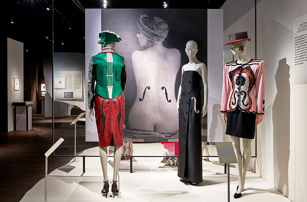 Items from Yves Saint Laurent's collection of 1965 with Man Ray's photograph <em></noscript>Le Violon d’Ingres</em> (1924) in the background.  Photo: Stany Dederen.  Courtesy of MoMu.” width=”1000″ height=”659″ srcset=”https://news.artnet.com/app/news-upload/2023/06/3-Man-Ray-and-Fashion-MoMu-22-April-13-August-2023-_-c-MoMu-Antwerp-Image-credit-Stany-Dederen24.jpg 1000w, https://news.artnet.com/app/news-upload/2023/06/3-Man-Ray-and-Fashion-MoMu-22-April-13-August-2023-_-c-MoMu-Antwerp-Image-credit-Stany-Dederen24-300×198.jpg 300w, https://news.artnet.com/app/news-upload/2023/06/3-Man-Ray-and-Fashion-MoMu-22-April-13-August-2023-_-c-MoMu-Antwerp-Image-credit-Stany-Dederen24-50×33.jpg 50w” sizes=”(max-width: 1000px) 100vw, 1000px”/></p>
<p id=