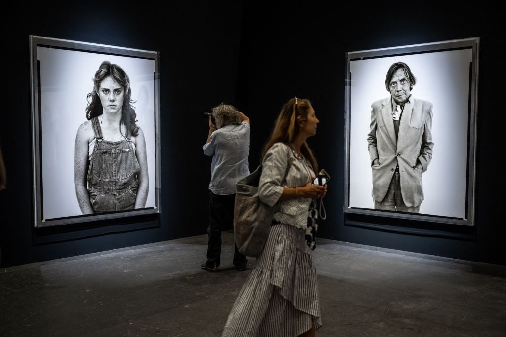 Visitors walk past pictures by US photographer Richard Avedon at "the Ten Exhibition Prints from In the American West, photographed 1979-1984" booth at the Art Basel fair for Modern and contemporary art, in Basel, Switzerland on June 13, 2023. Photo by Fabrice Coffrini/AFP via Getty Images.