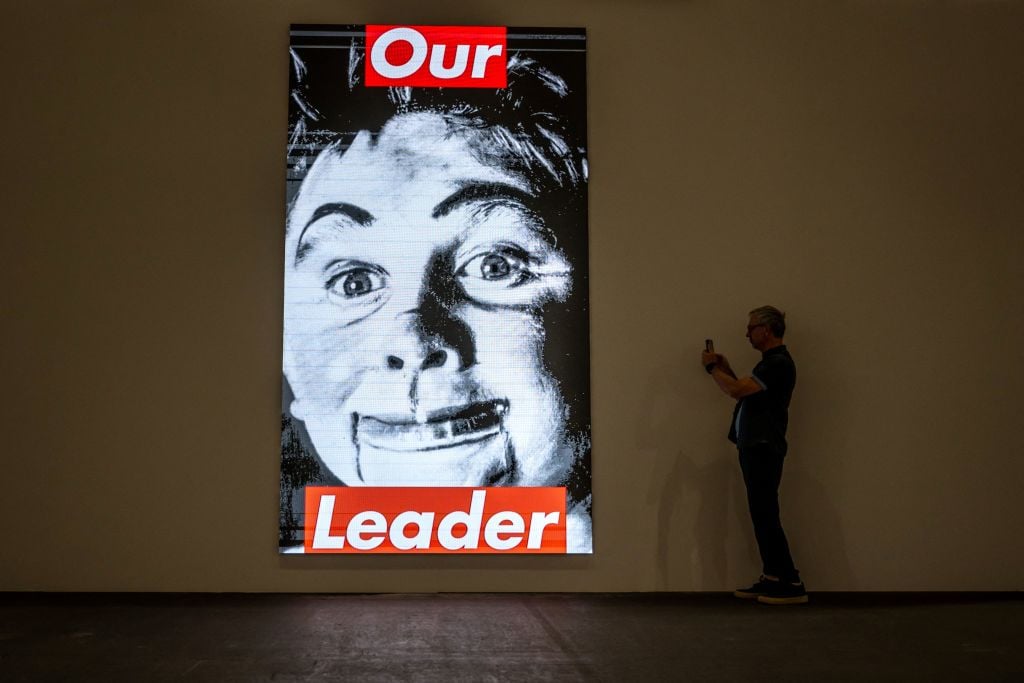 A visitor takes a picutre next to "Untitled (Our Leader)" 1987/2020 by US conceptual artist Barbara Kruger, displayed at the Unlimited section of the Art Basel fair for Modern and contemporary art, in Basel, Switzerland on June 13, 2023. Photo by Fabrice Coffrini/AFP via Getty Images.