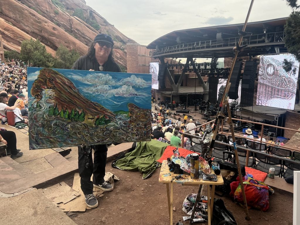 Keith "Scramble" Campbell with his painting of King Gizzard performing at Red Rocks Amphitheatre outside Denver. Photo by Sarah Cascone. 