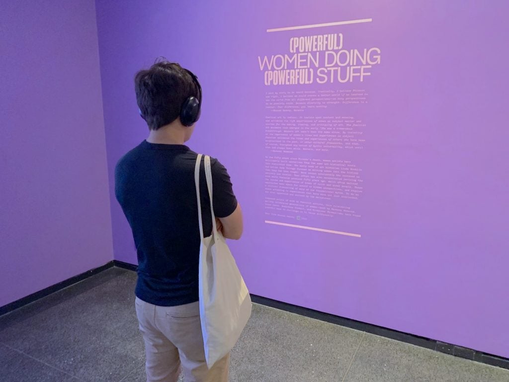 A visitor reads a wall text in "It's Pablo-matic"