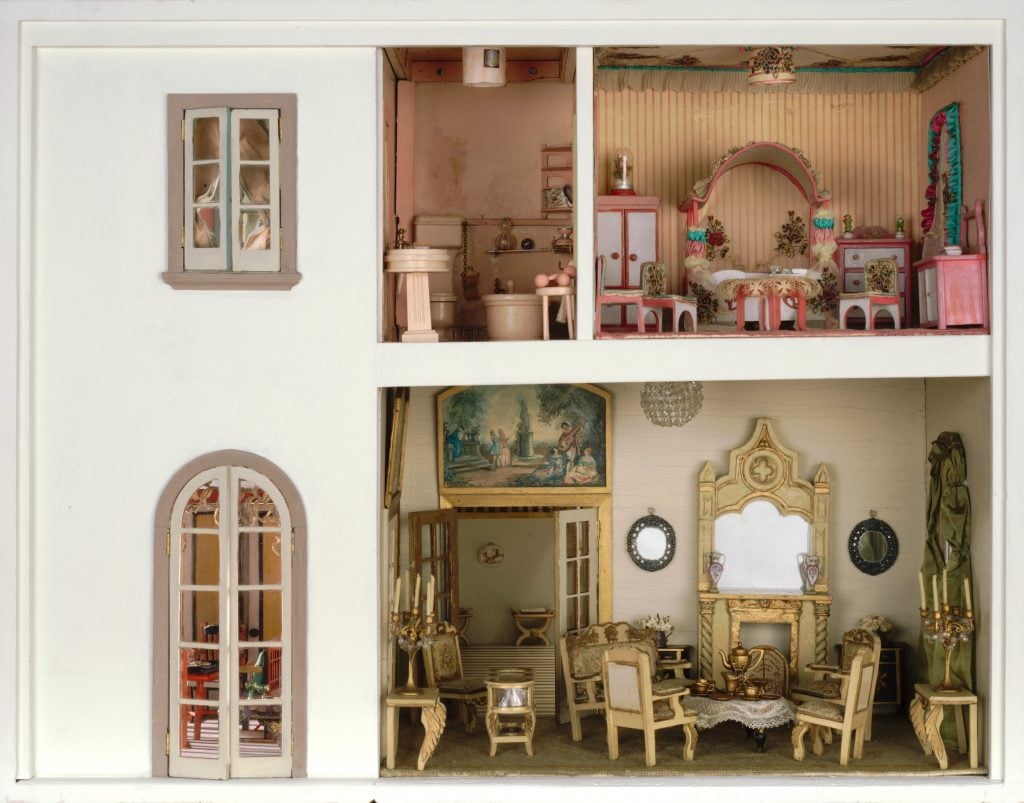 Ornate dollhouse living room and dining room with vintage furniture and chandeliers.