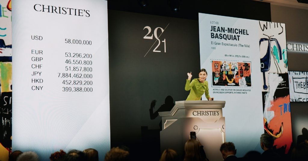 Auctioneer Georgina Hilton sells the top lot of Christie’s 21st century evening sale, Jean-Michel Basquiat’s <i>El Gran Espactaculo</i> (1983). Courtesy of Christie's Images Limited 2023.