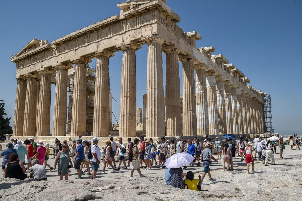 Atop the Acropolis ancient hill, tourists visit the Parthenon temple during a heat wave on July 20, 2023 in Athens, Greece. The Acropolis of Athens and other archaeological sites in Greece announced reduced opening hours due to the heatwave conditions. Photo by Milos Bicanski/Getty Images.
