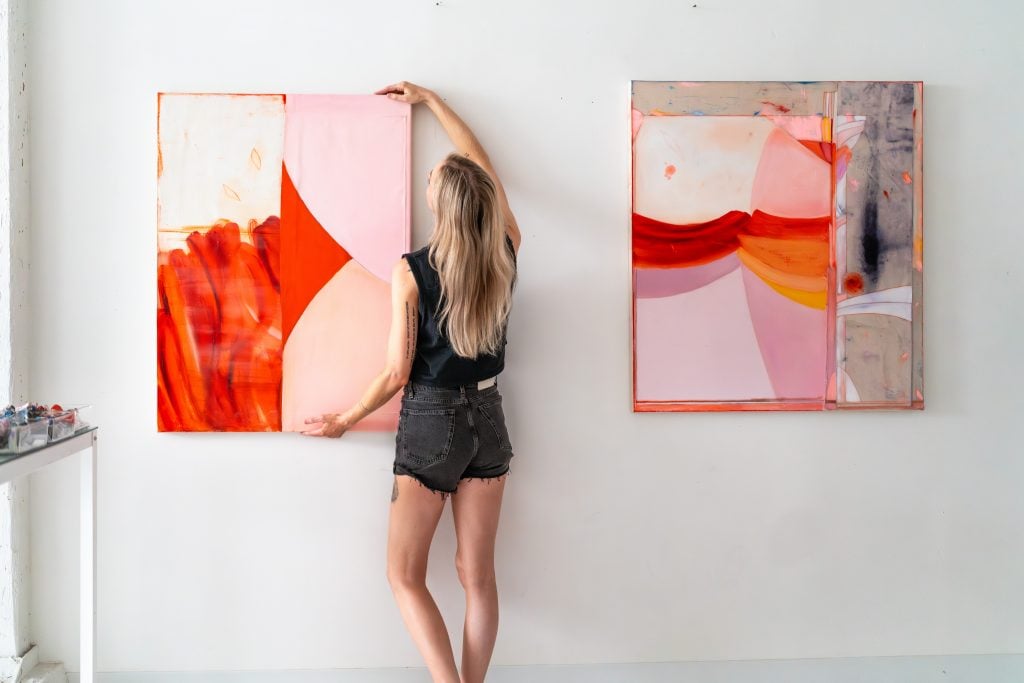Dana James hangs paintings in her studio.