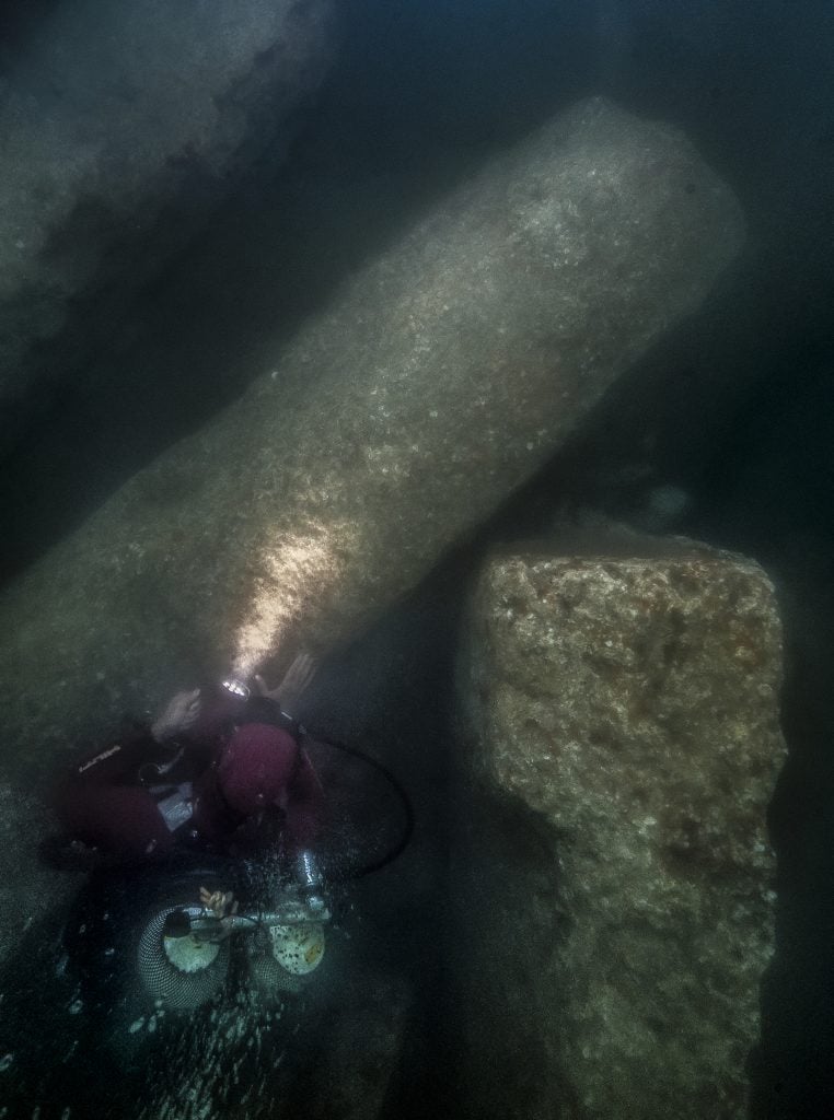 After excavation, an archaeological diver gazes at the huge blocks of the Amun temple, which fell in the mid-second century B.C.E. in the south canal of Thonis-Heracleion. They were discovered under nearly 10 feet of hard clay. Photo by Christoph Gerigk ©Franck Goddio/Hilti Foundation.