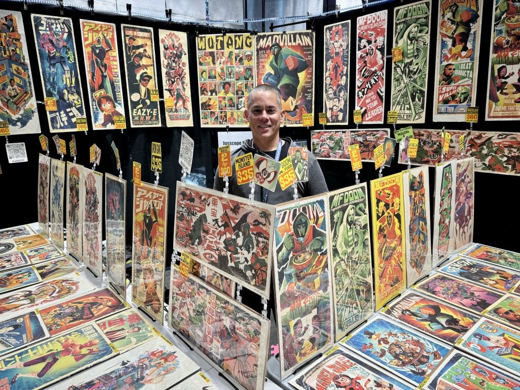Justin Orr with his work at 2023 New York Comic Con. Photo by Sarah Cascone. 