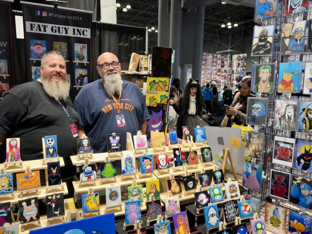 Brendan Shaw and Peter Vasquez of Fat Guy Inc. with their work at 2023 New York Comic Con. Photo by Sarah Cascone. 
