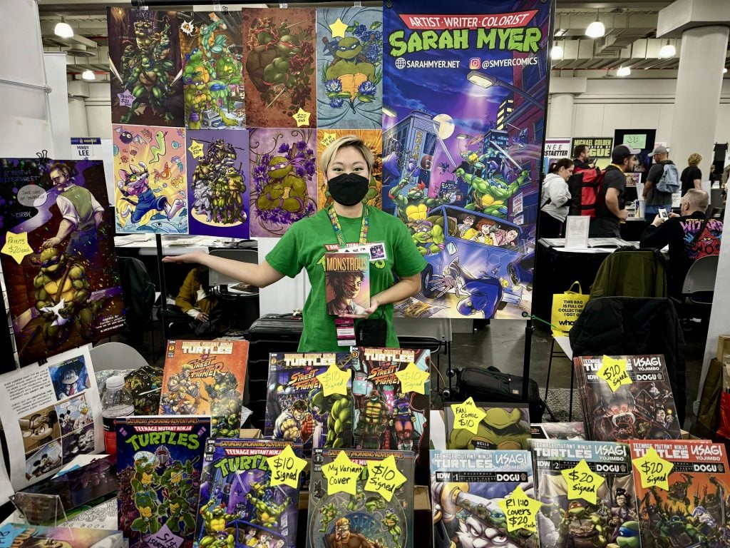 Sarah Myer with her work at 2023 New York Comic Con. Photo by Sarah Cascone.