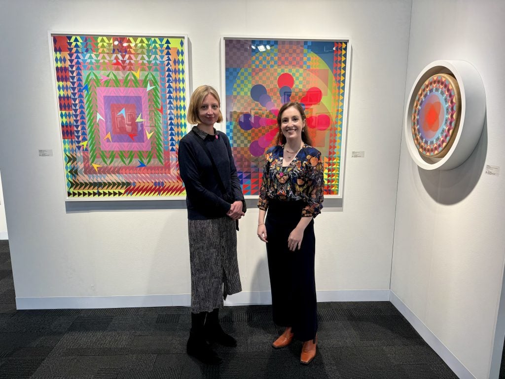 British Museum curators Catherine Daunt and Rose Taylor with works by Jeffrey Gibson from Tandem Press at the IFPDA Print Fair. Photo by Sarah Cascone. 