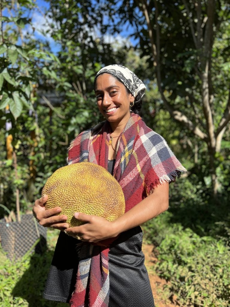 Sadaf holding jackfruit grown in the forests of grown in Haiti.