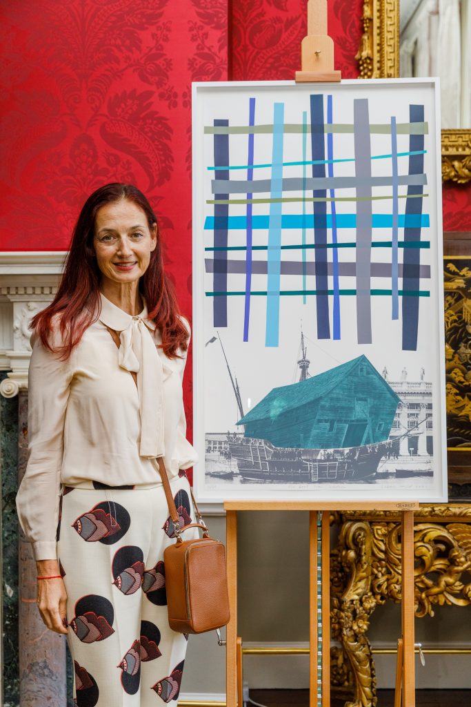 A woman standing beside an abstract painting.