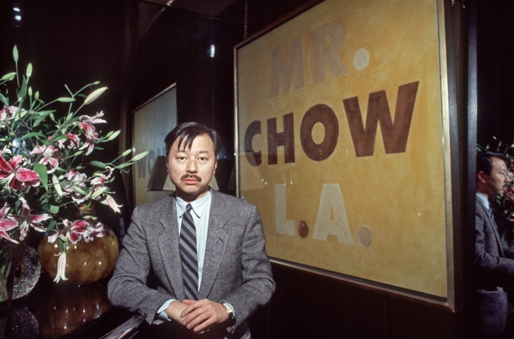 Michael Chow with a 1973 painting by Ed Ruscha at the Los Angeles outpost of Mr. Chow's restaurant. Photo by Allan Tenenbaum, courtesy of HBO.