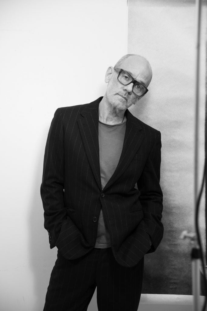 Musician and artist Michael Stipe posing against a wall