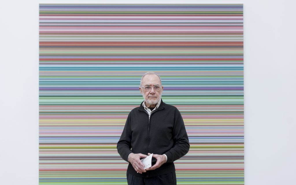 The 92-year-old artist Gerhard Richter stands in front of a horizontal color painting.