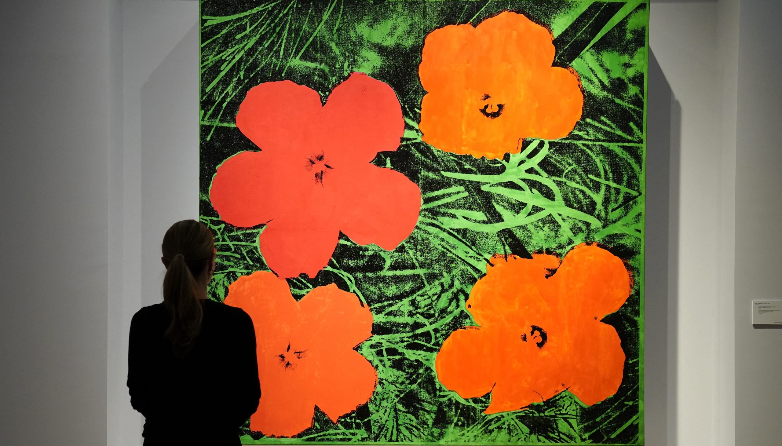 a woman looks at pictures of flowers on a wall