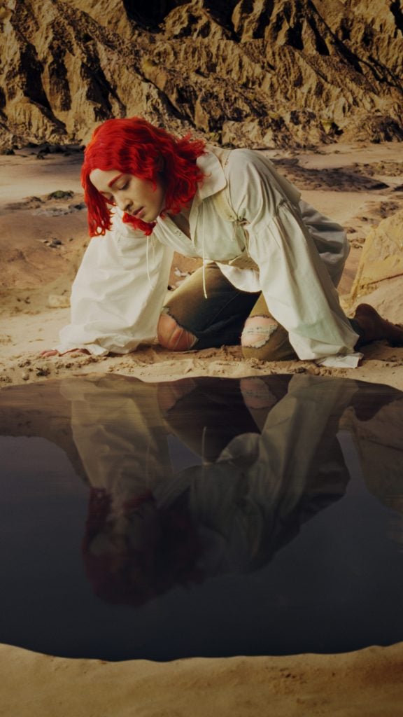an artwork depicting a person with red hair looking into a pool with their reflection visible