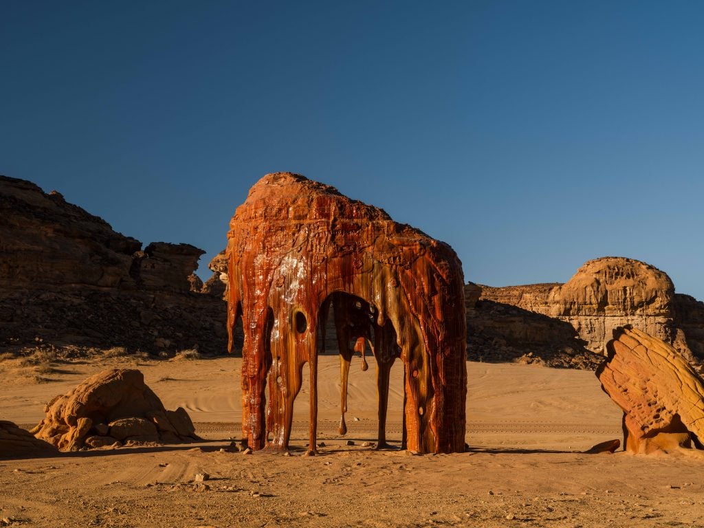 photograph of a large stalagmite like sculpture with varnished surface in the desert