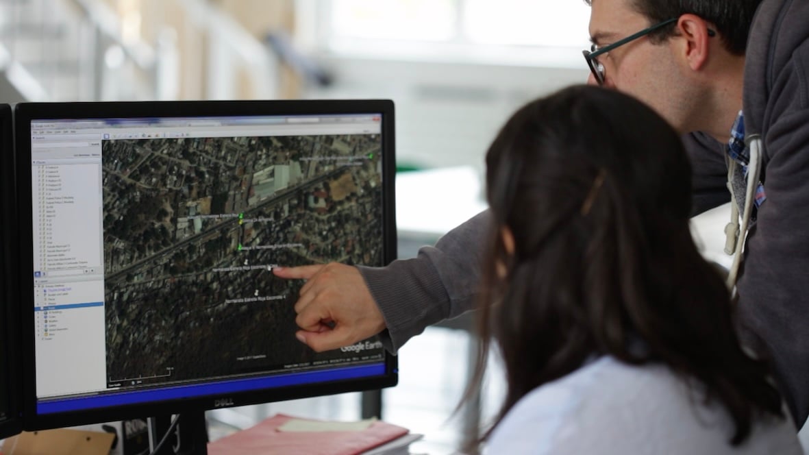 A man and woman look at satellite imagery on a computer screen.