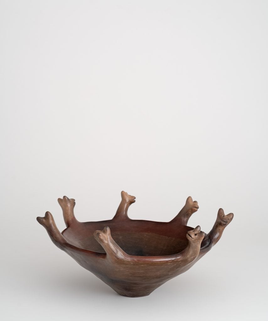 The image is of a brown clay bowl with 7 animal heads