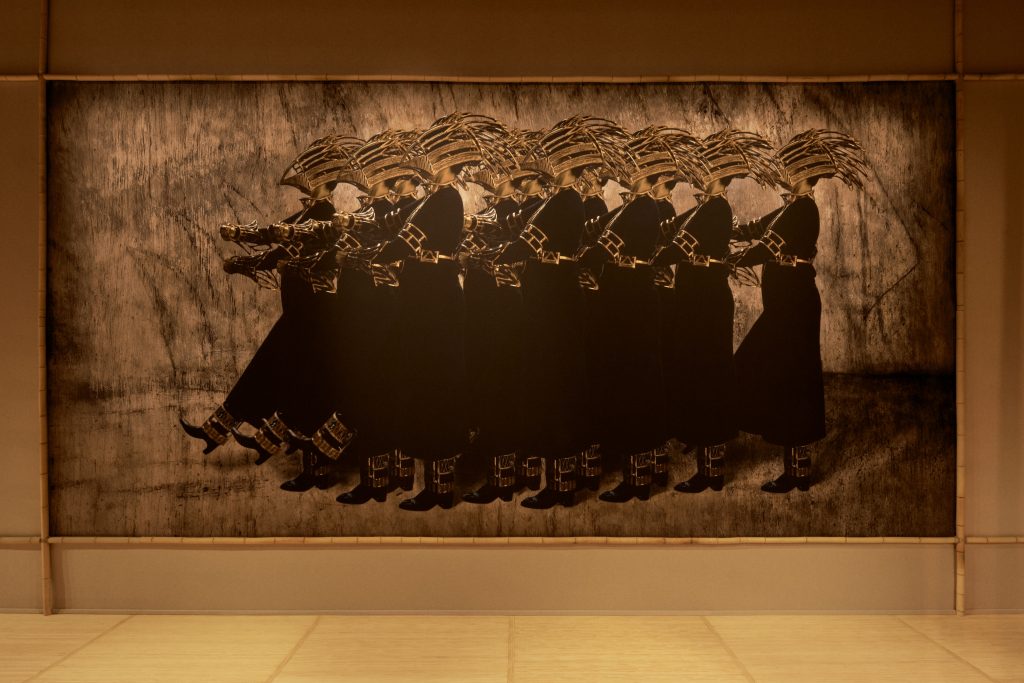 A mural depicts a group of marching female warriors wearing helmets. 