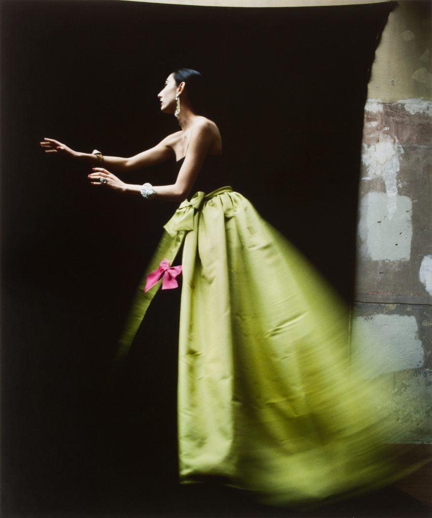 David Seidner profile photograph of a woman in a ysl voluminous chartreuse skirt with a small pink bow reaching out infront of her