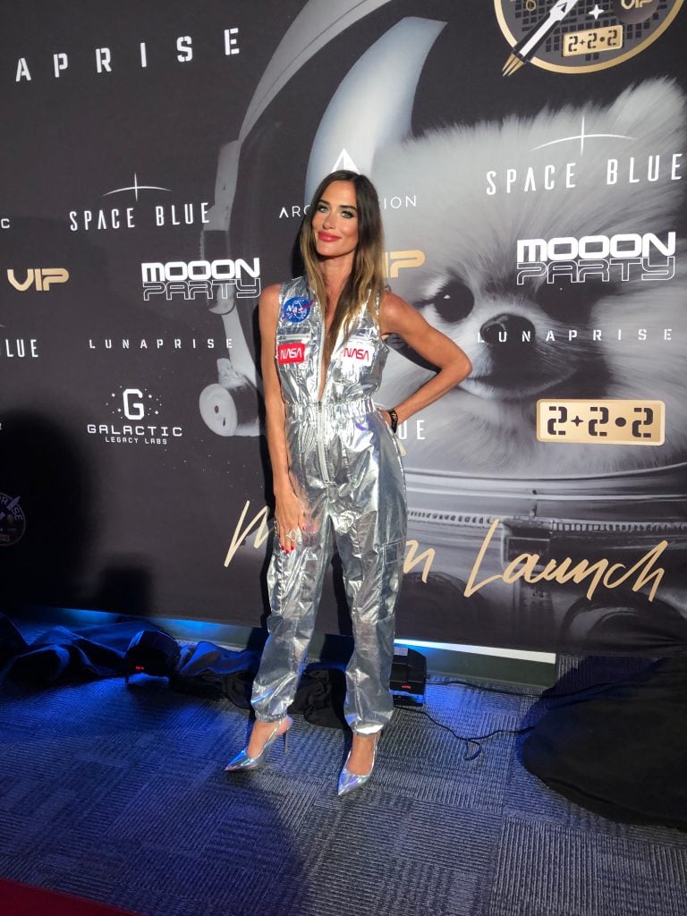 A woman in a silver jumpsuit with NASA patches