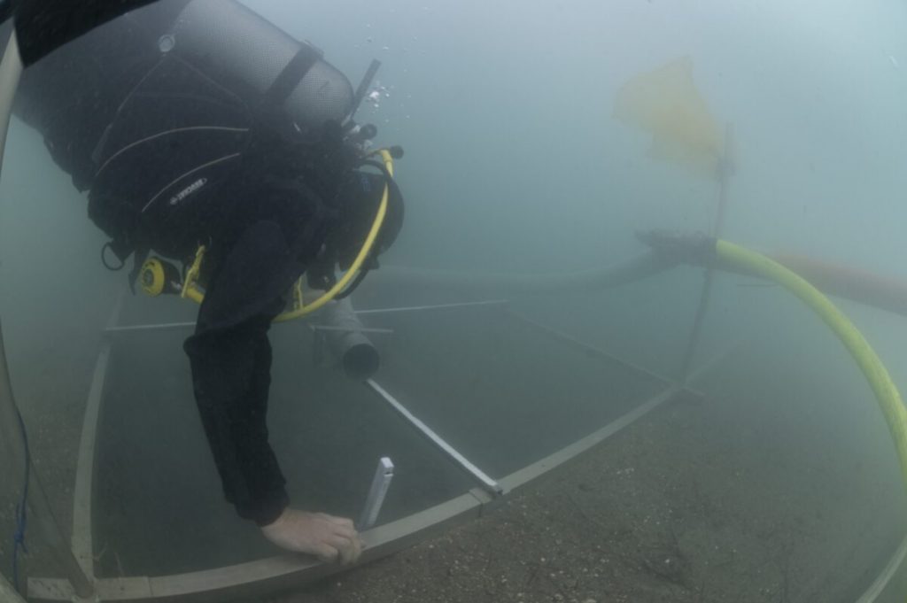 A diver seen underwater with metal rigging.