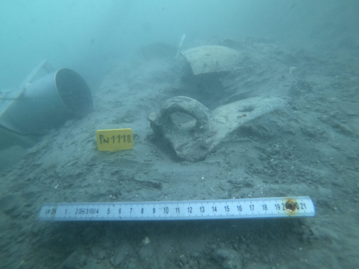 Various ceramic shards embedded in silt underwater.