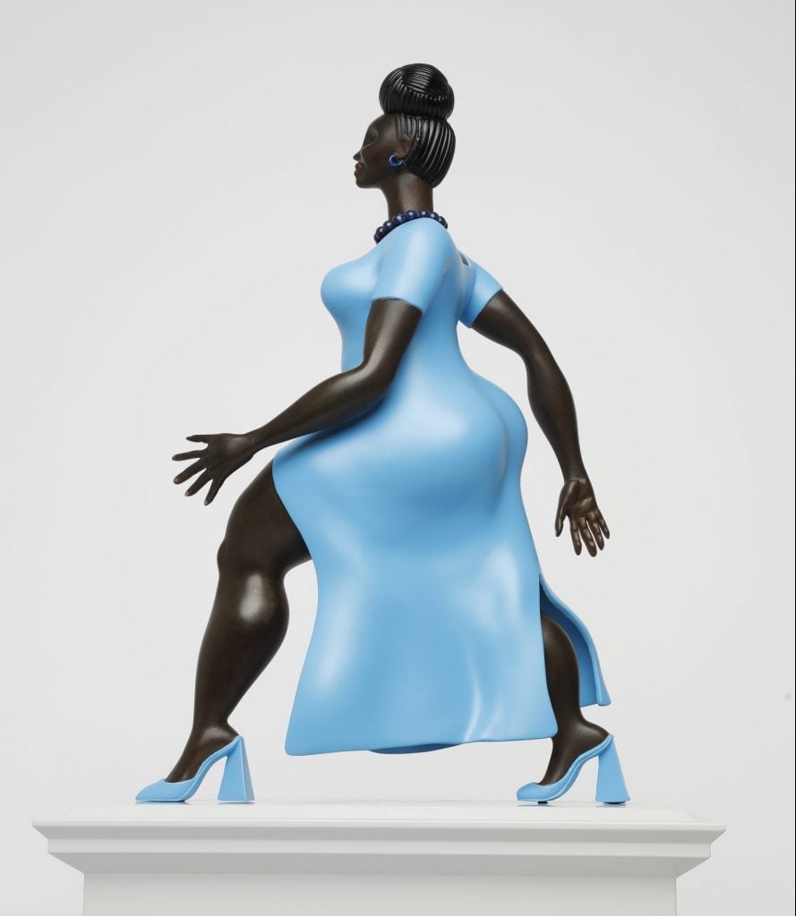 A sculpture depicting a modern woman in color in a pale blue dress and high heels
