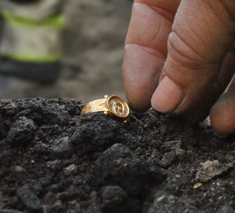 A hand reaching out to a 15th-century gold ring, found on a medieval site in Kamar, Sweden.