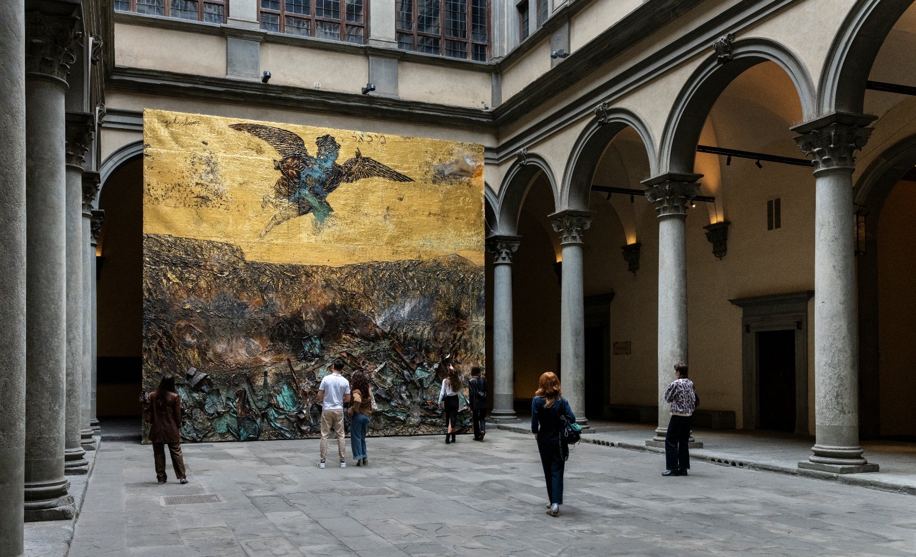 a large golden painting with an angel inside a classical courtyard