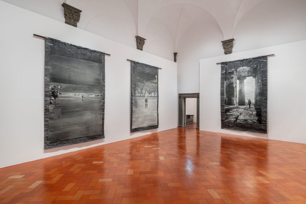 白色画廊空间的墙壁上挂满了闪亮的灰色画作。